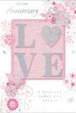 This anniversary card appears as a gentle tribute to enduring romance, crafted in a soft harmony of pastel pinks, pearlescent whites, and silvery greys that would feel perfectly at home in a quiet Hackney Marshes cottage. At its heart, the word LOVE stands proudly in raised, velvety letters, edged with fine glitter that twinkles between blush and silver tones. The letter O is subtly transformed into a shimmering heart shape, its textured surface catching the light as though dusted with starlight, inviting fingertips to linger over the design. Behind this central motif, a smooth blush panel sits against a lighter pink ground, creating a layered effect that feels both intimate and elegant.   

Around the central word, delicate blooms in blush, mauve, and soft ivory appear to unfurl across the card with a watercolour softness. Their petals are defined with slender ink lines and silver accents, suggesting the careful, practiced hand of a florist sketching out a romantic bouquet on a quiet afternoon in Hackney Marshes. Slender vines curl gracefully between the blossoms, while tiny petals, swirling flourishes, and subtle butterfly shapes add a sense of gentle motion, like a light breeze moving through flowers near the marsh paths.   

Above and below the central motif, beautifully balanced text reads On Our Anniversary and I love you today and always, in a refined, flowing script that matches the card's understated grace. The overall composition evokes a serene celebration of shared years, making this card feel like a keepsake designed to accompany a pastel-toned anniversary arrangement delivered by a nearby Hackney Marshes florist to homes overlooking the greenery and waterways.